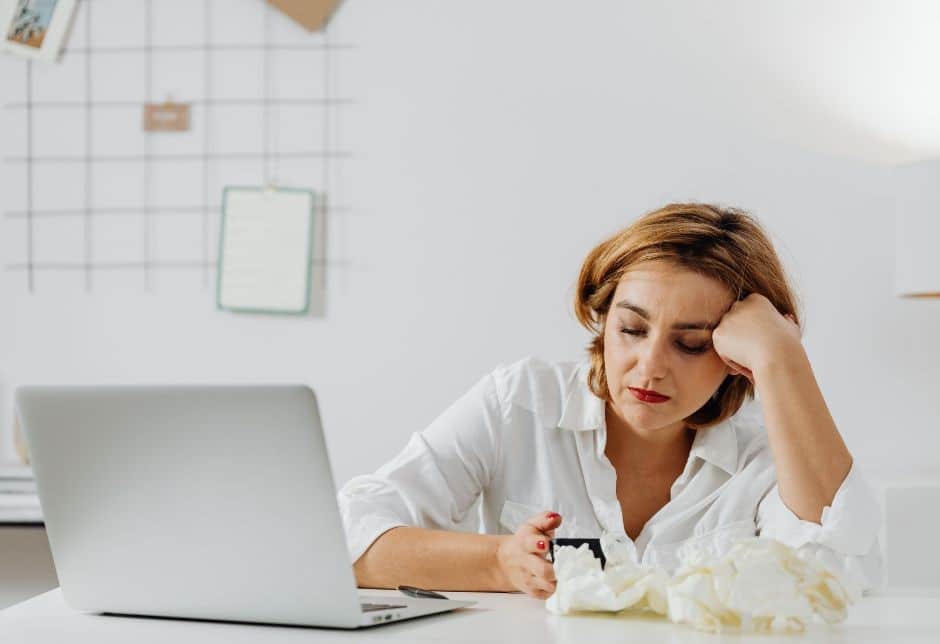 Zdjęcie przedstawia kobietę siedzącą przy biurku przed komputerem